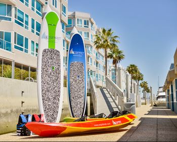 A surfboard with a green and blue design is leaning against a building.